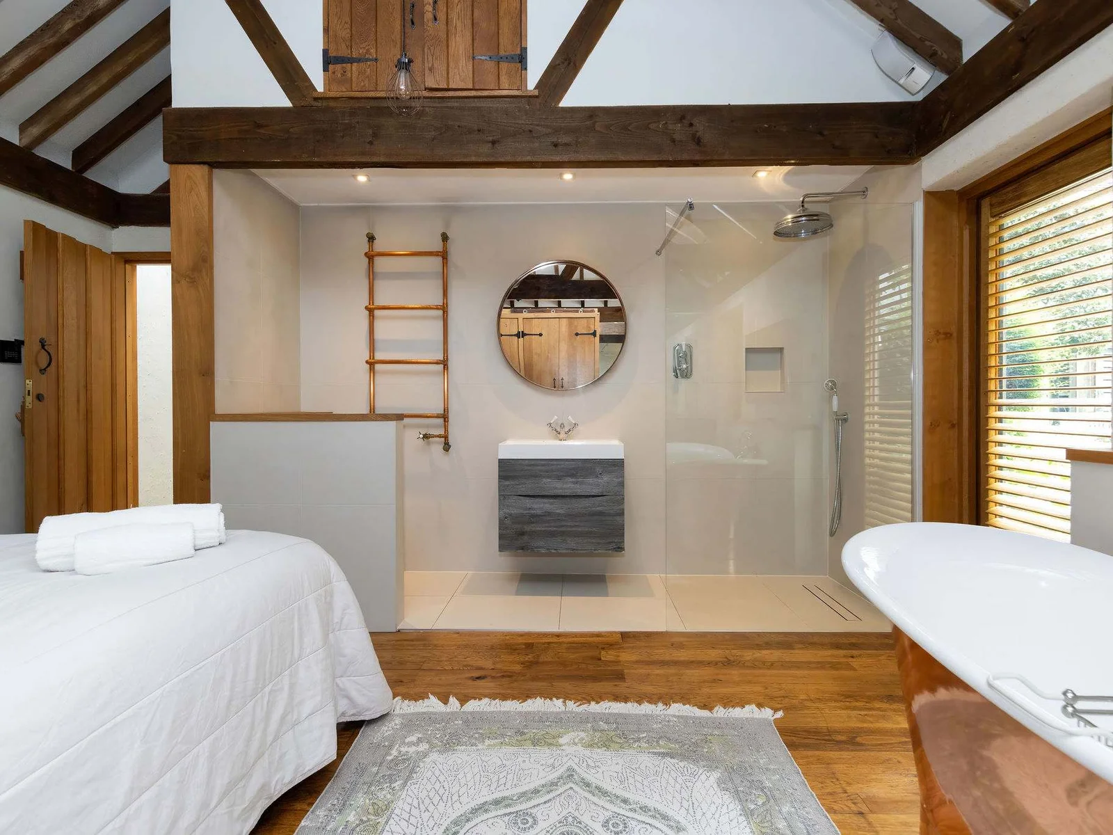 A luxurious open en-suite with rainfall shower and statement freestanding bath
