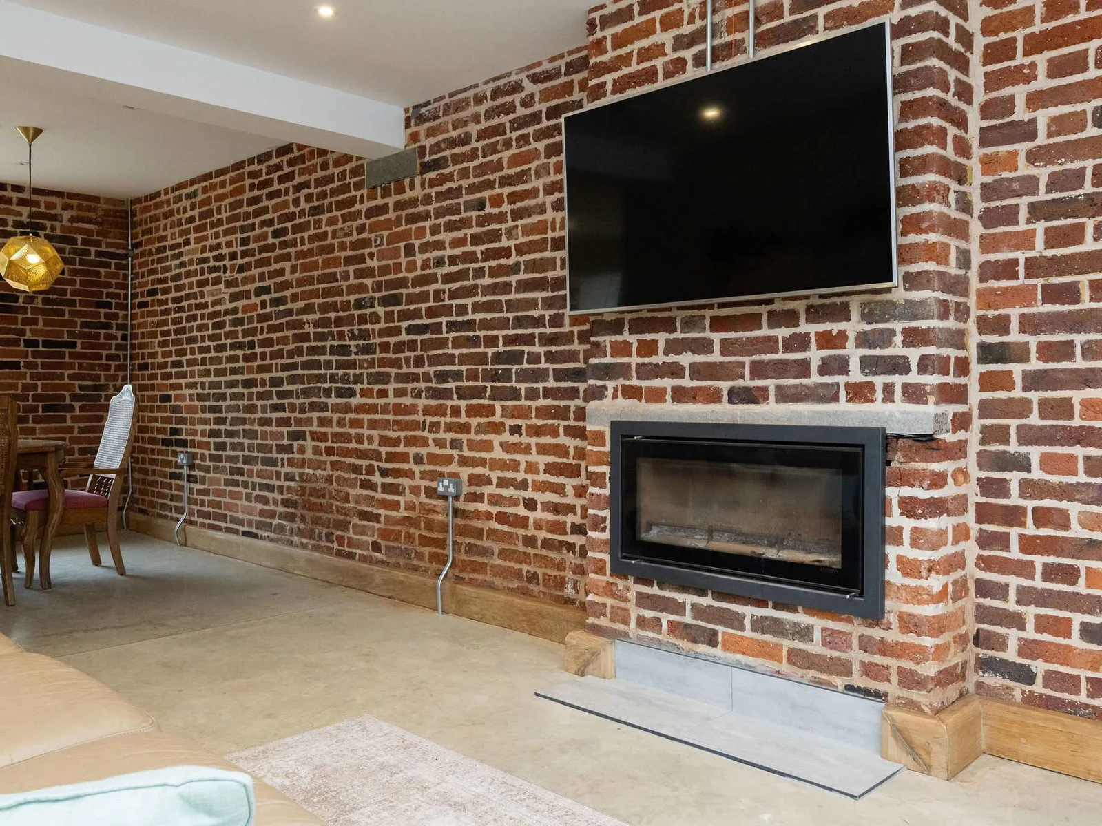 The feature brick wall with its mounted TV and fireplace creates a warm and inviting space to relax with family in the evenings.