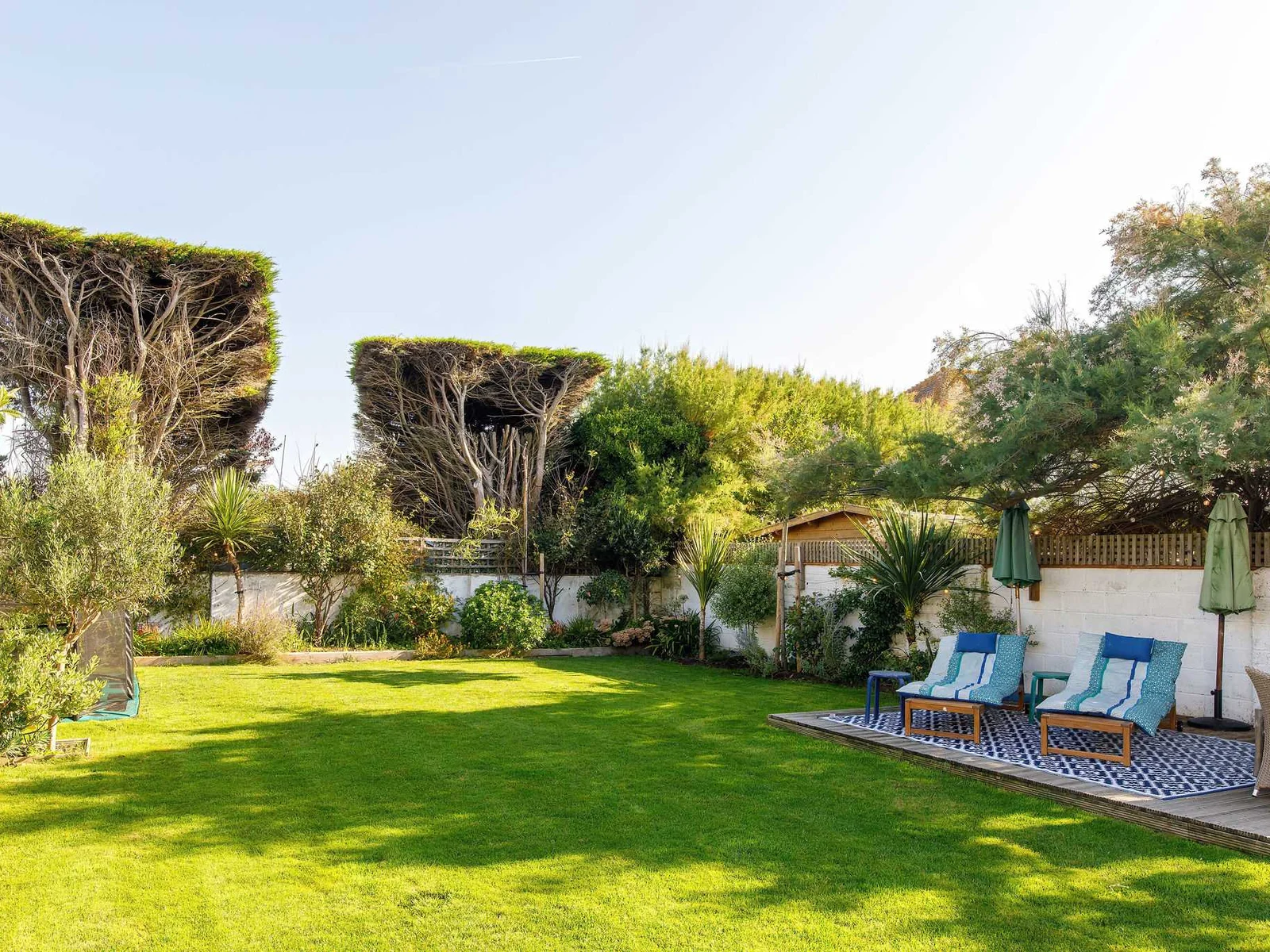 There is a large decked area with dining furniture and sunloungers.