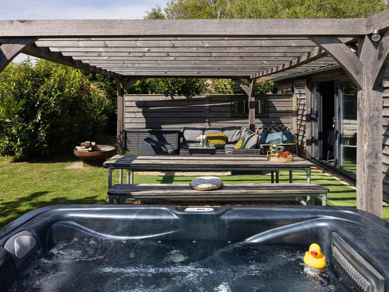 Indulge in countryside relaxation with a private hot tub and spacious outdoor lounge area.