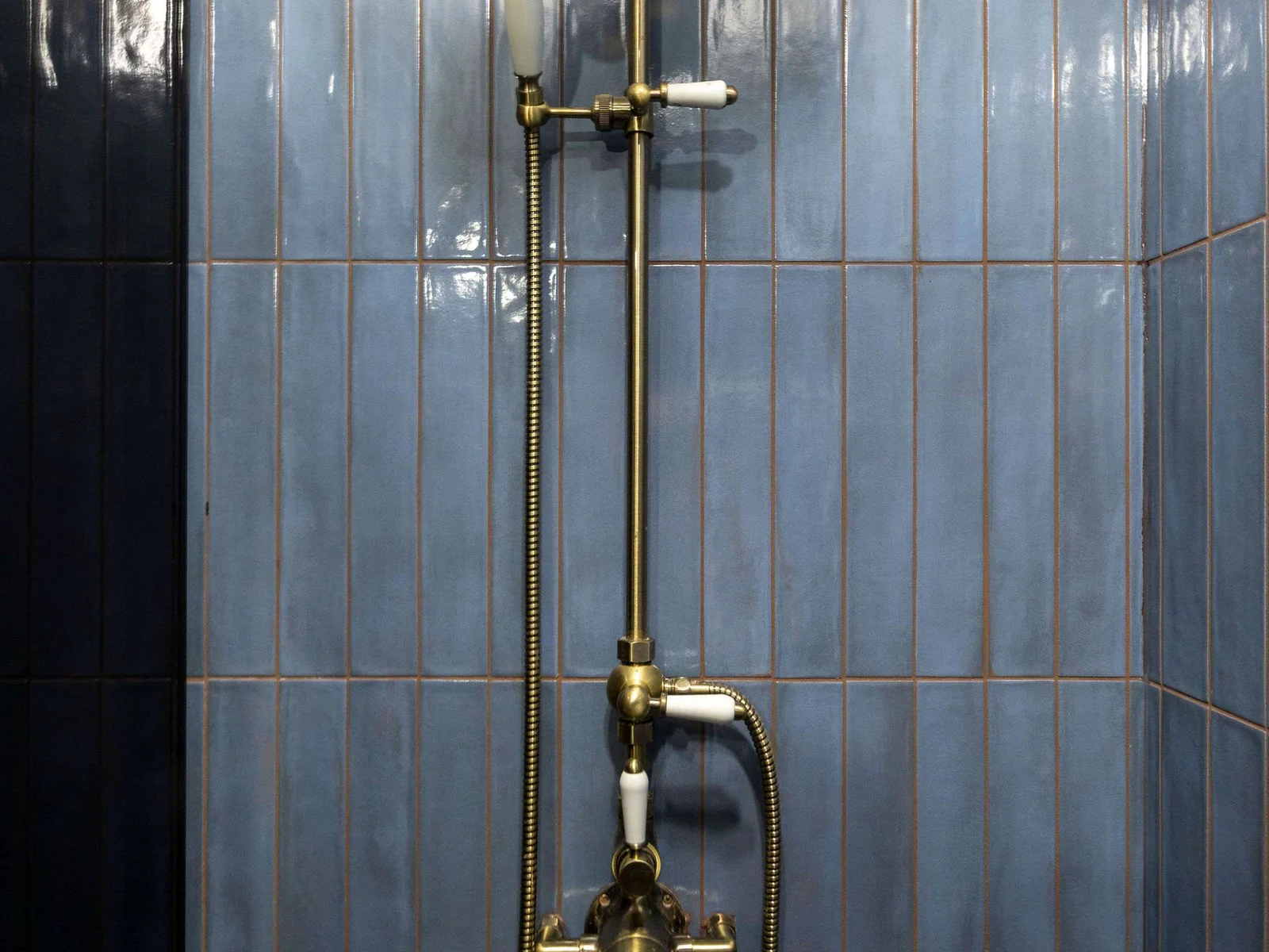 Relax in the spacious walk-in shower, featuring elegant gold fittings and tiled walls.