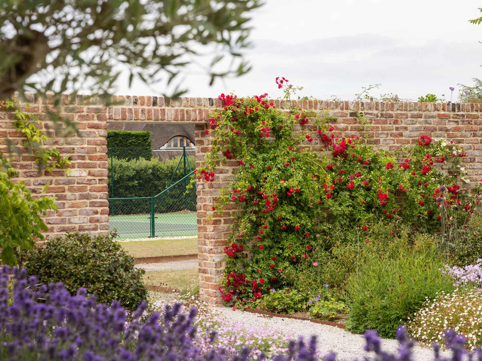 Walled garden with vibrant flowers and tennis court access