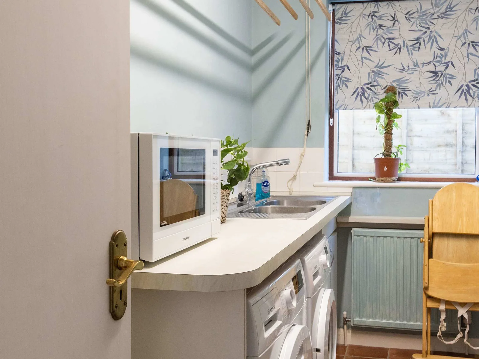 A separate utility room with microwave, washing machine, dryer and children's high chair.