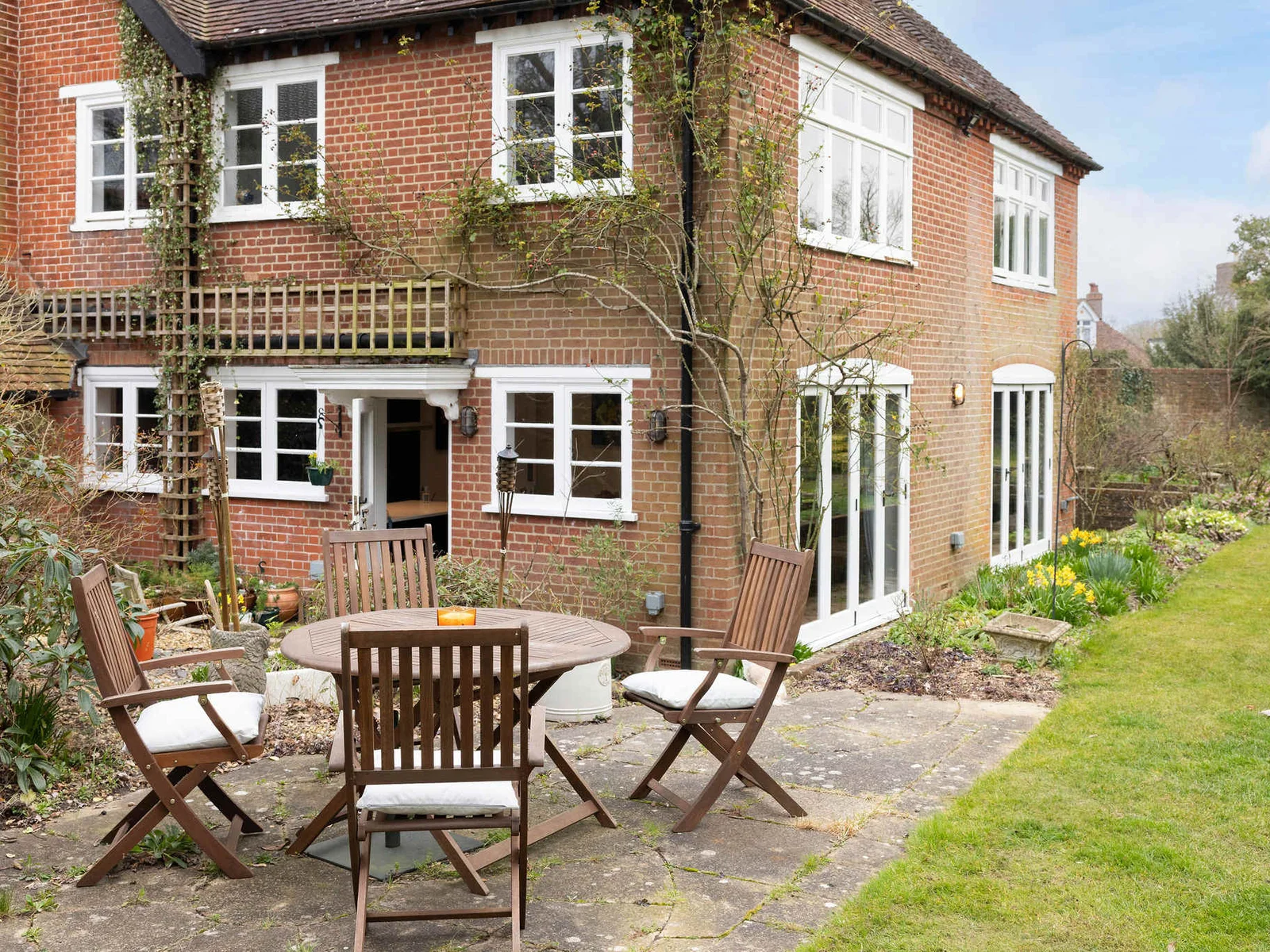 A charming brick home with lush greenery and an inviting outdoor dining area
