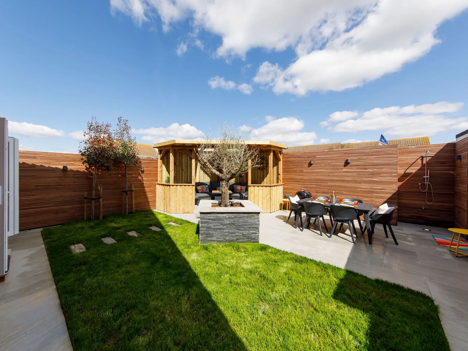 There is a lawned area, patio with dining furniture and beautiful pergola seating area.