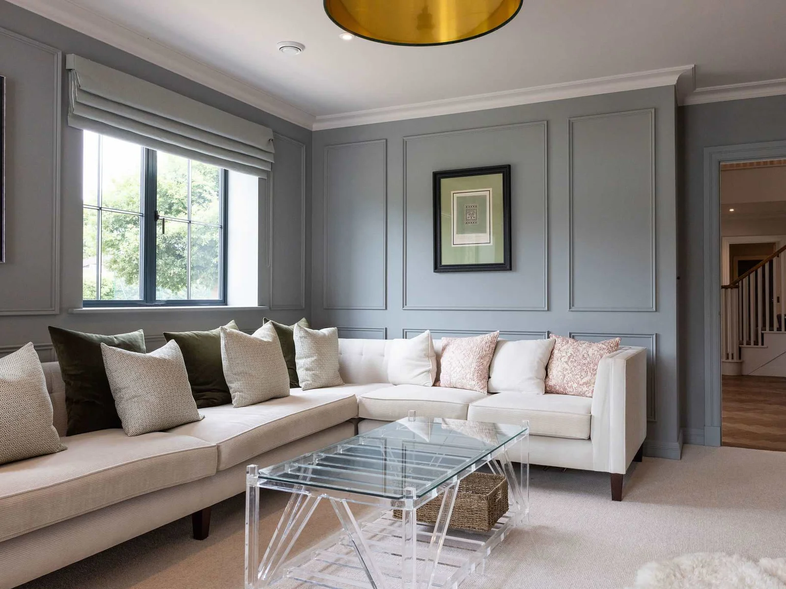 A stylish living area with a large corner sofa, statement lighting, and a calming colour palette