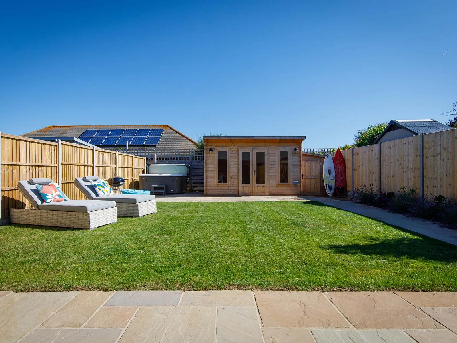 Relax in the pristine garden, which has a patio, grassy area with sun loungers and a hot tub!