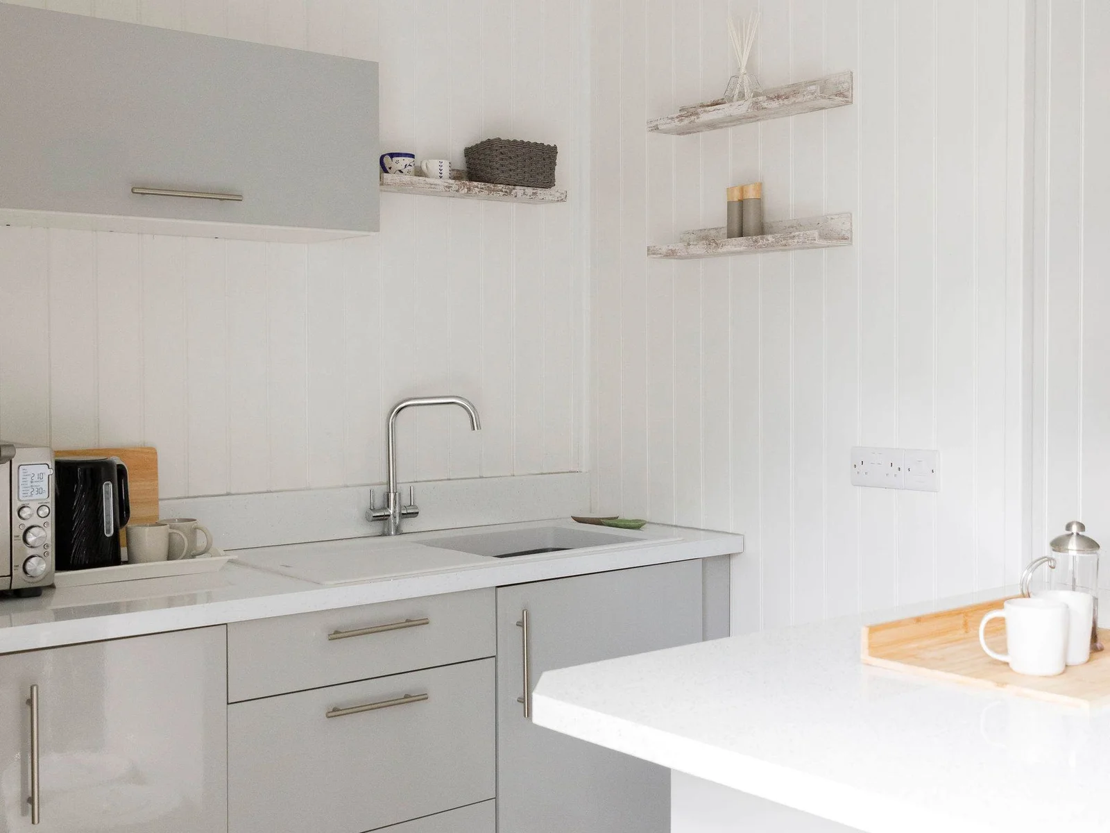 The grey cabinetry and white wood gives this kitchenette a clean and spacious feel.