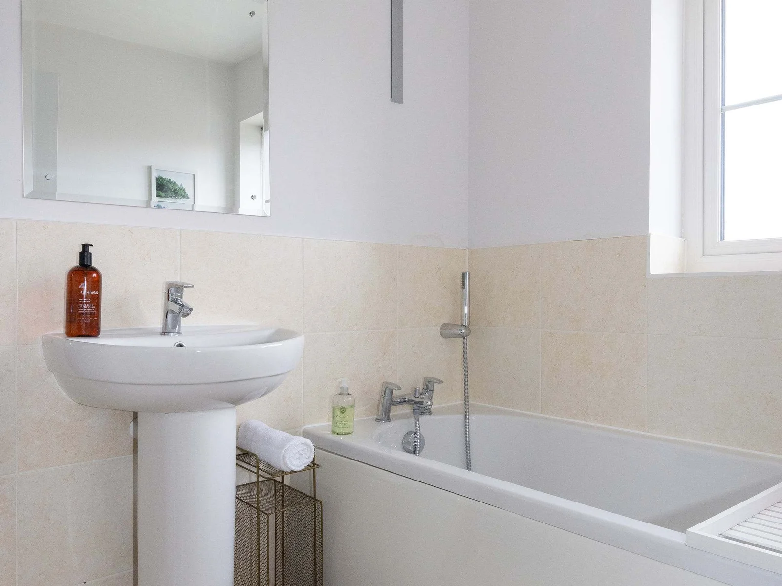 The family bathroom has a bath with handheld shower head, as well as sink, WC and heated towel rail.