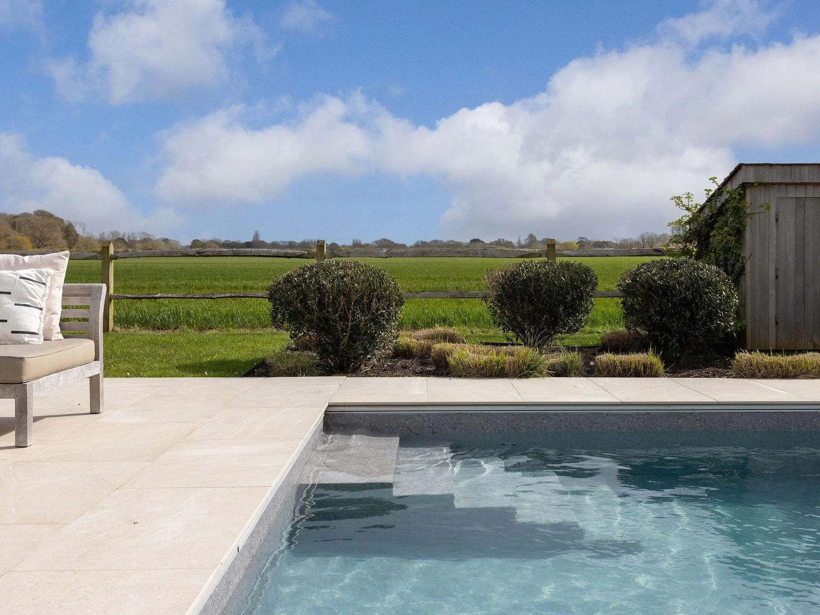 Relax by the heated pool with beautifully manicured hedges and sweeping countryside views beyond.