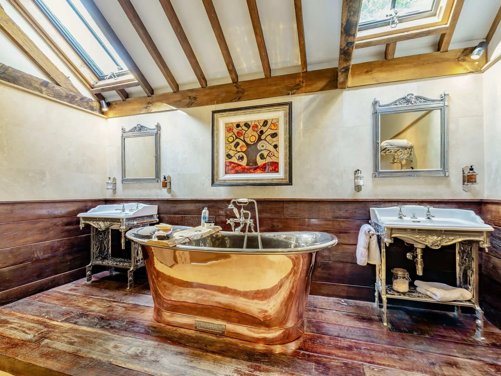 A showstopping master bathroom with copper roll-top bath, twin basins and exposed beams