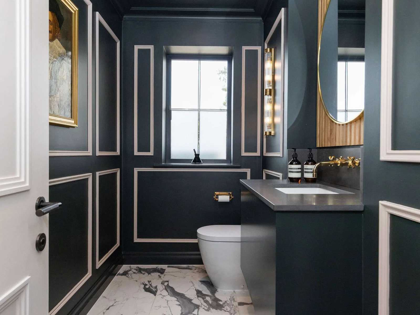A luxurious ground floor cloakroom with panelled walls, marble flooring, and gold accents