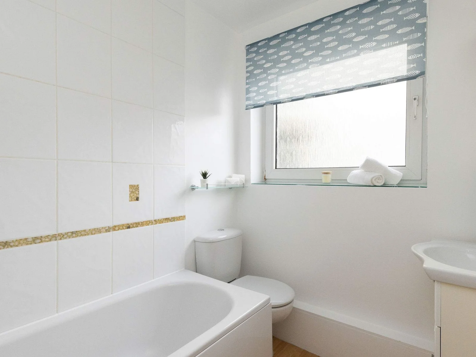 Fresh, bright bathroom with bathtub and overhead shower, perfect for relaxing after a day at the beach.