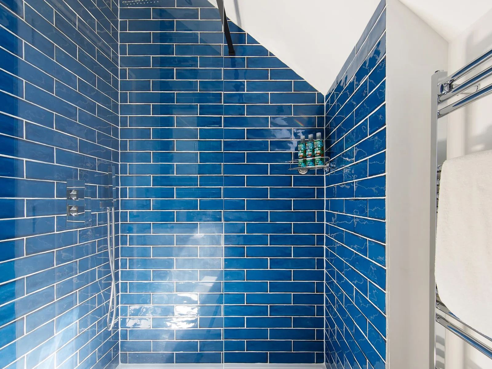 The large shower is tiled with beautiful ocean blue tiles.