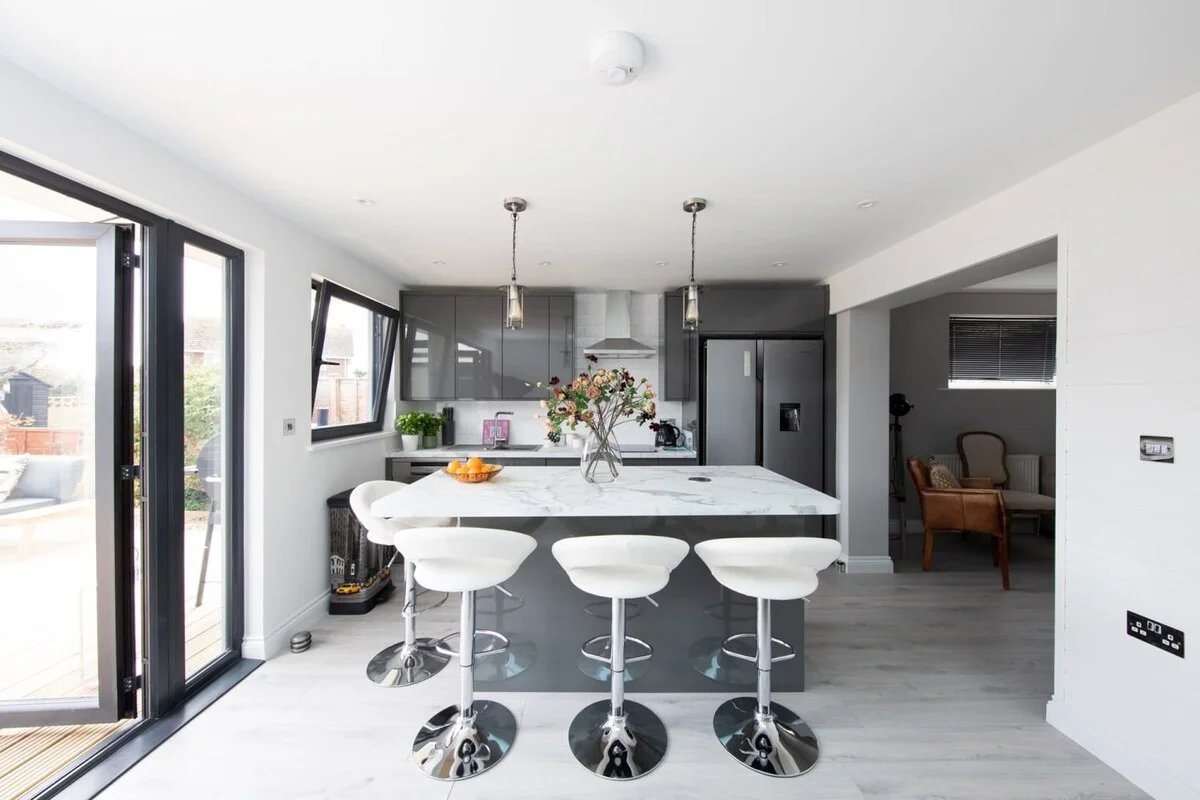 Dark cabinetary with spacious white countertops and a large kitchen island, provide plenty of working space as well as breakfast bar.