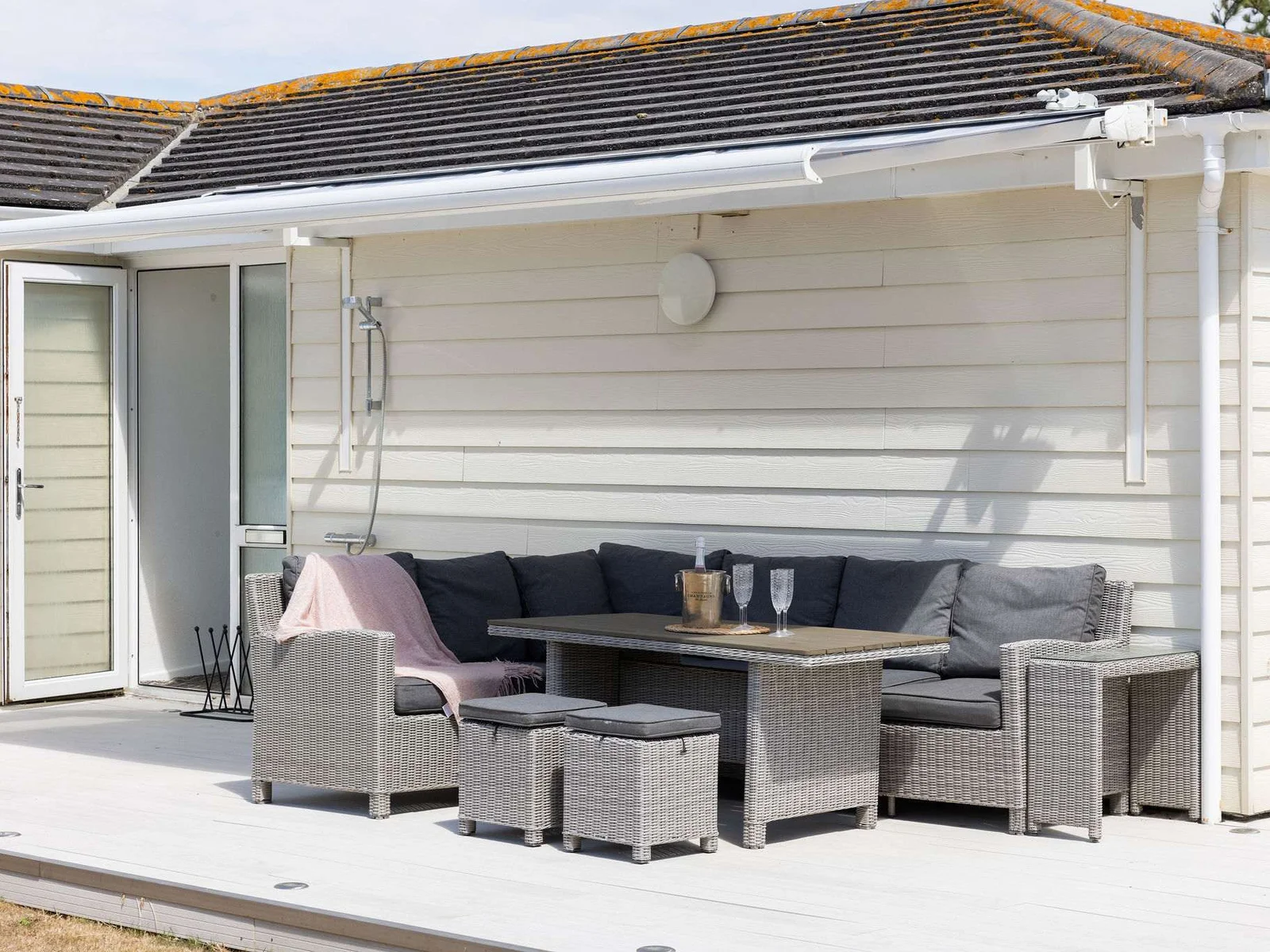 Comfy corner seating with a table and outdoor shower—perfect after the beach