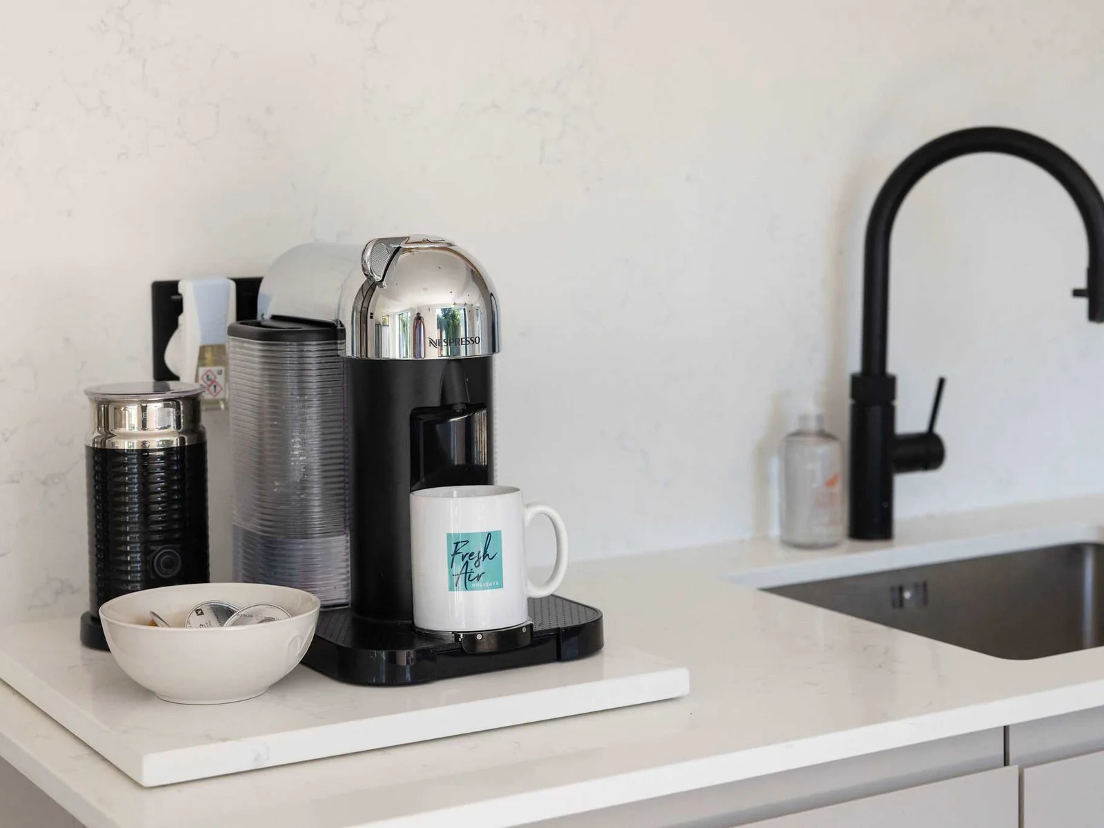 A sleek coffee station with a stylish pod machine, crisp worktops and elegant finishes — a polished little corner for slow mornings and freshly brewed coffee.