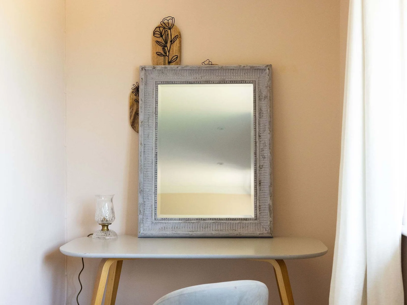 A dedicated dressing area with a statement mirror, slim console and comfortable chair — a lovely little spot to get ready for the day.