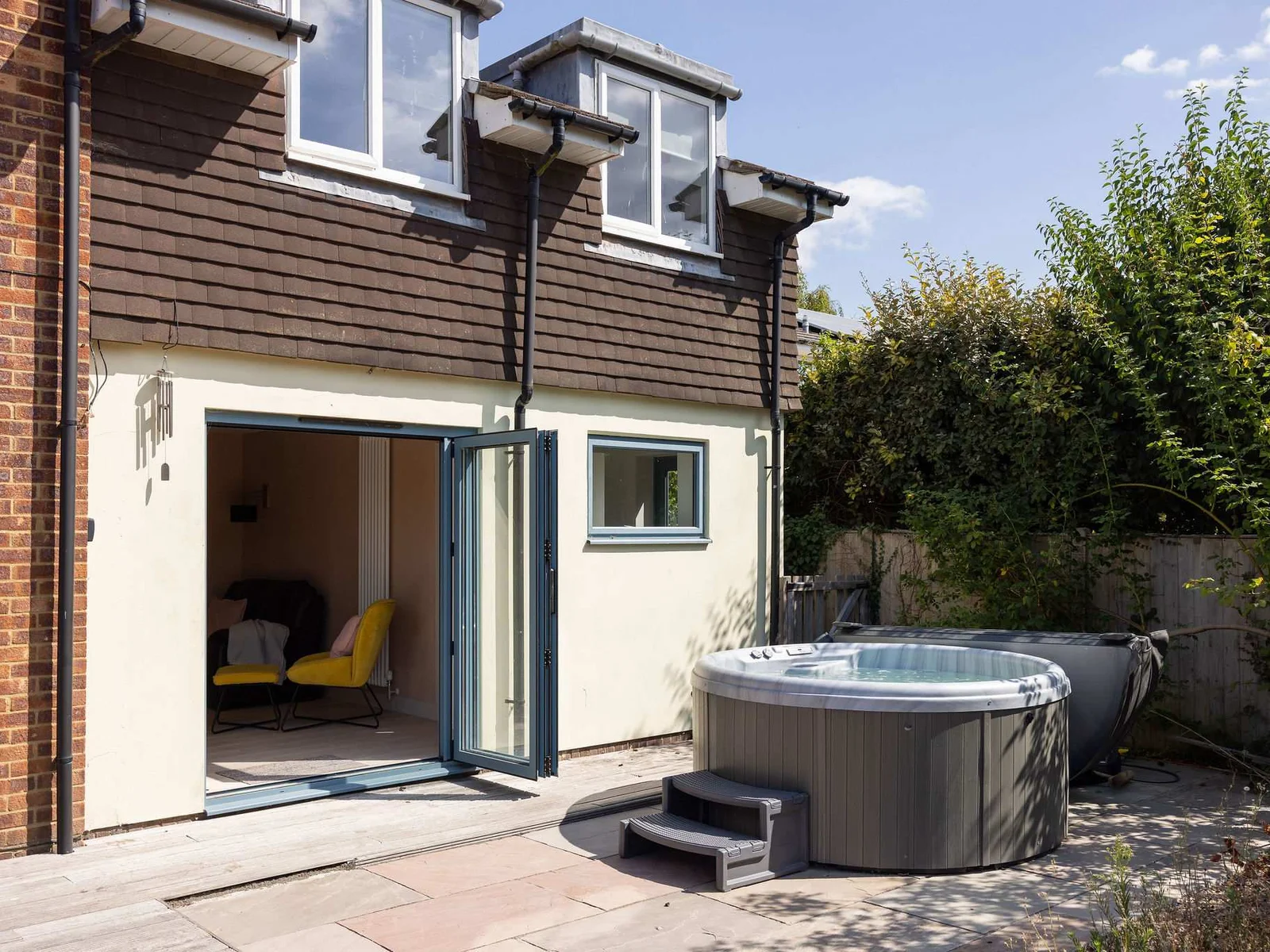 Private hot tub set on the sunny rear patio, with direct access into the house and a peaceful, enclosed garden setting for relaxed outdoor living.