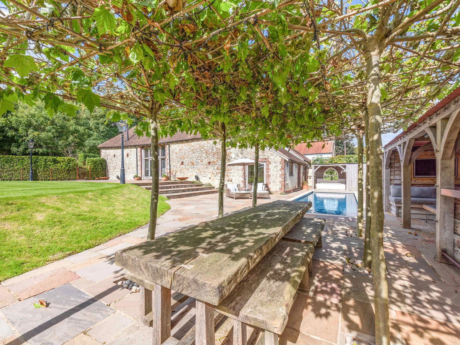 Shaded outdoor dining beside the pool, perfect for long summer lunches