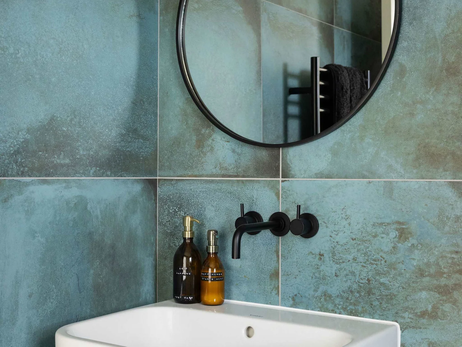 Stylish details at every turn — contemporary basin, matte black fixtures, and textured tiling.