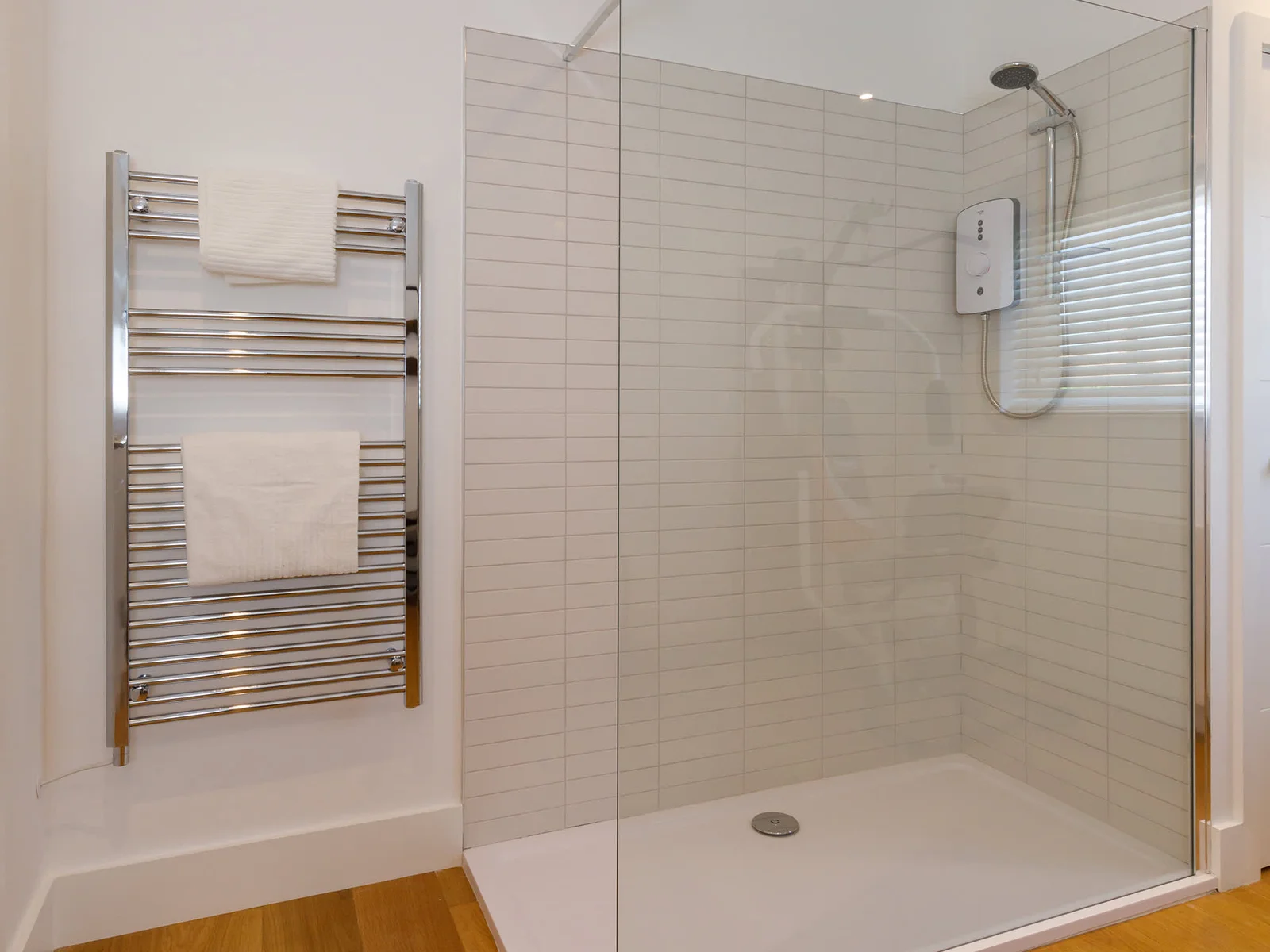 The spacious walk-in shower in the bathroom with wooden floors
