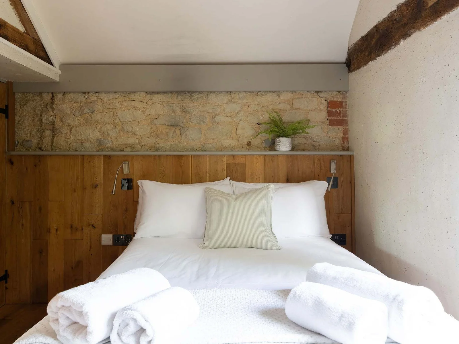 A peaceful bedroom with character stone walls and soft, neutral styling.