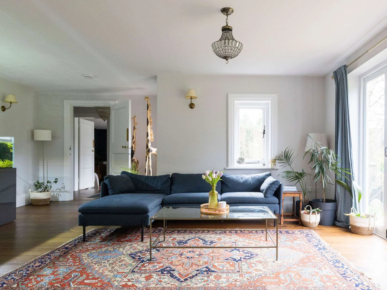 A stylish lounge with deep blue seating, large windows, and lush greenery