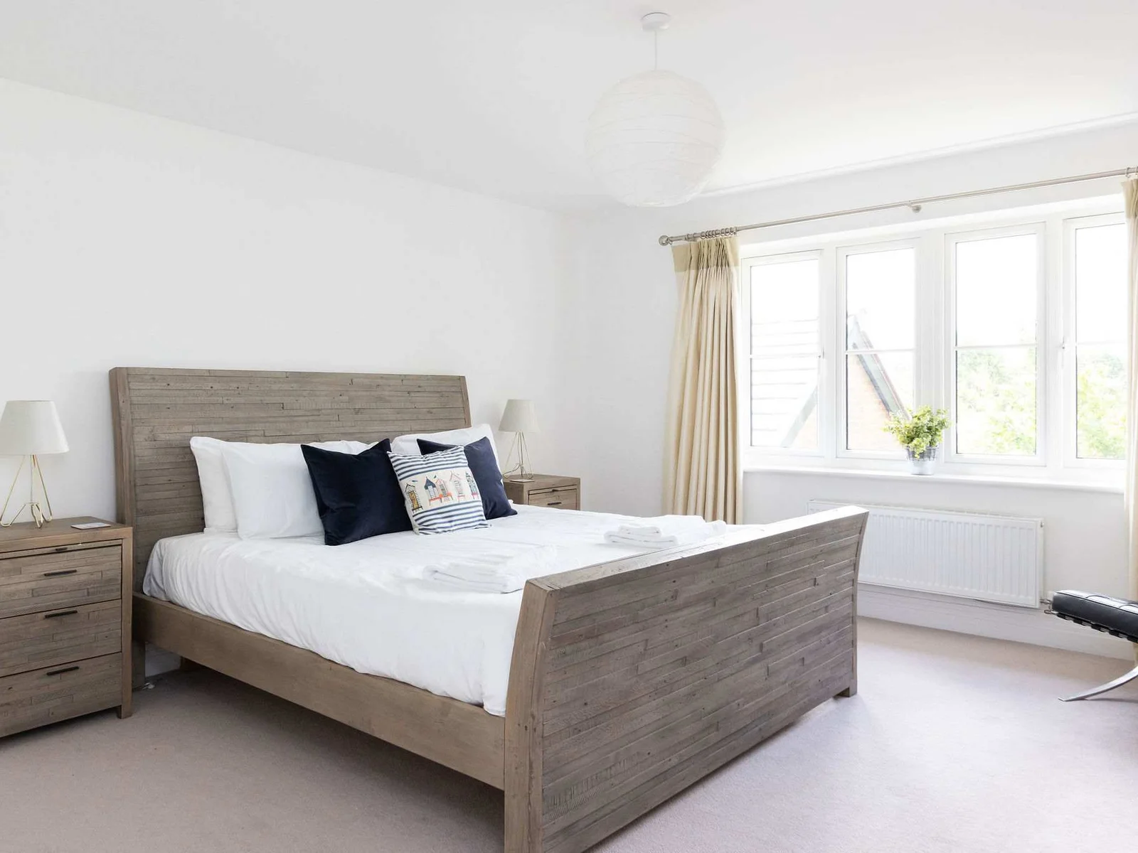 Welcome to the spacious master bedroom, a bright and serene retreat featuring a comfortable king-size bed and stylish wooden furniture.