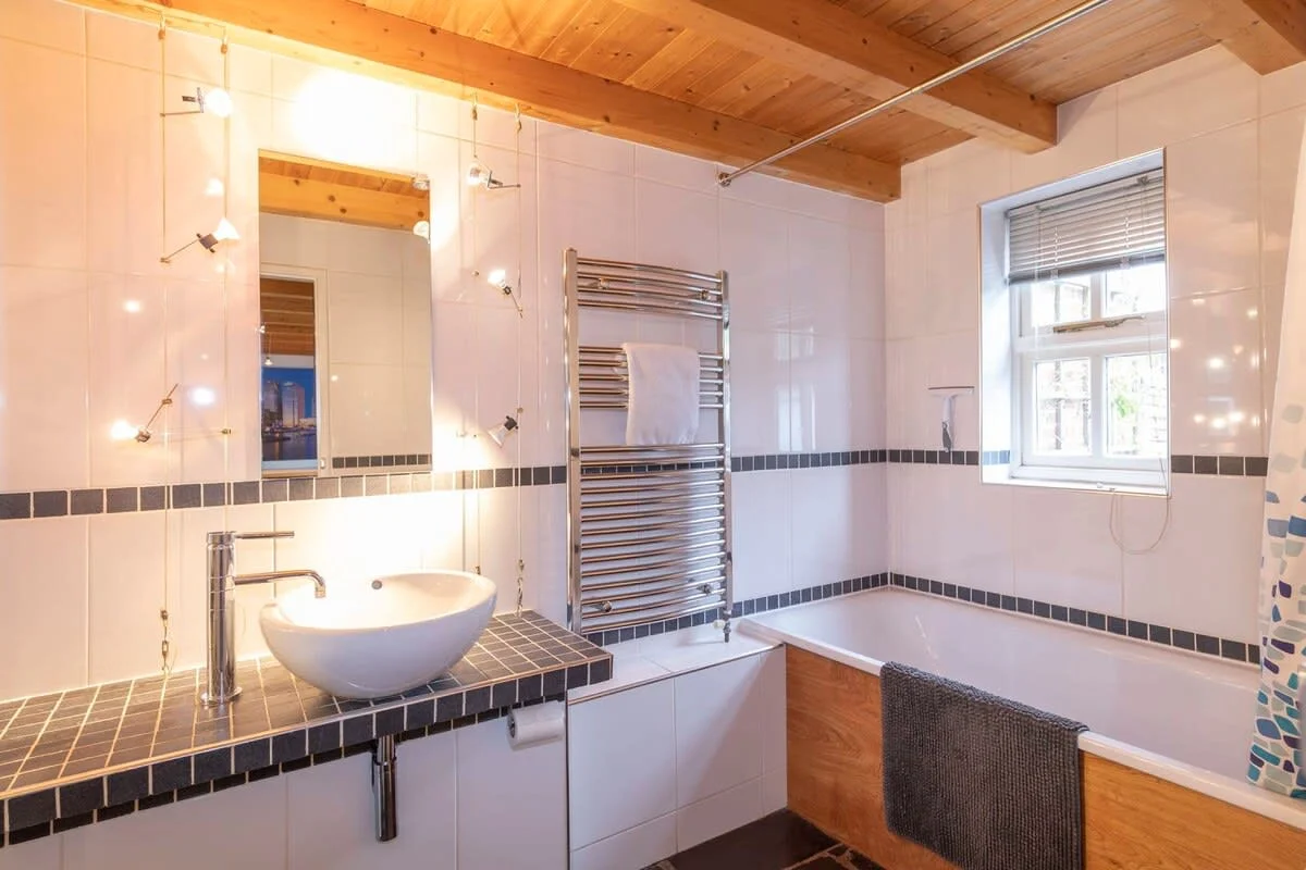Family bathroom: relaxing bath with an overhead shower, sink and toilet.