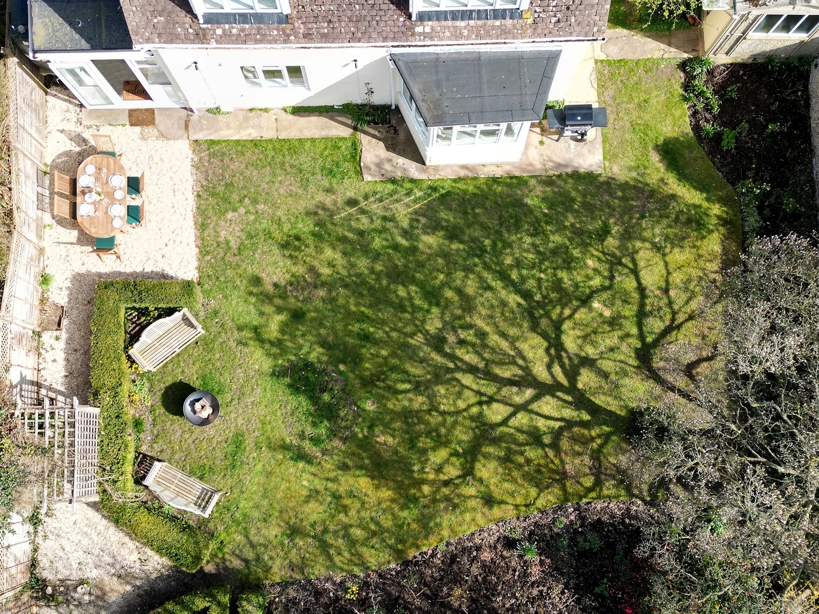 There is bench seating by the fire pit, outdoor dining furniture and a gas BBQ.