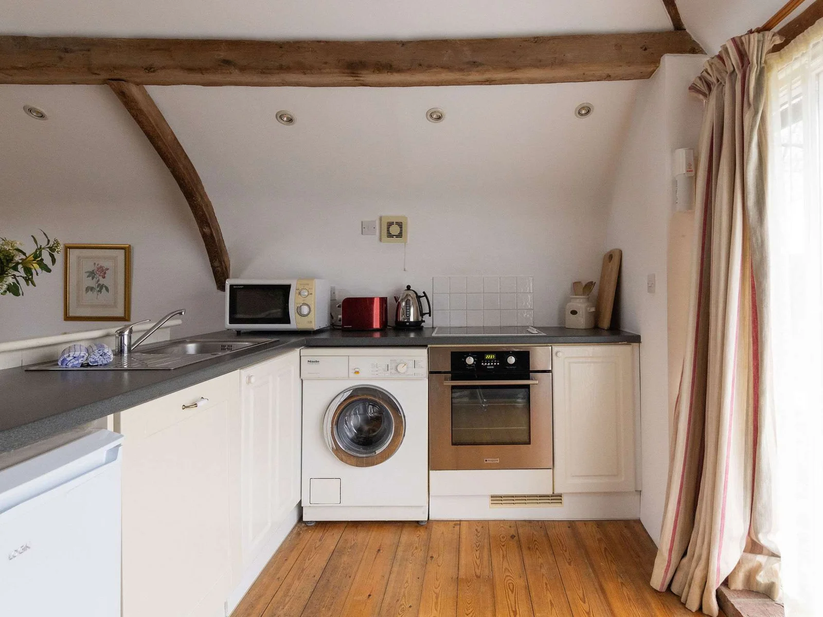 Simple kitchen with oven, hob, microwave, and washing machine, everything you need for relaxed stays.