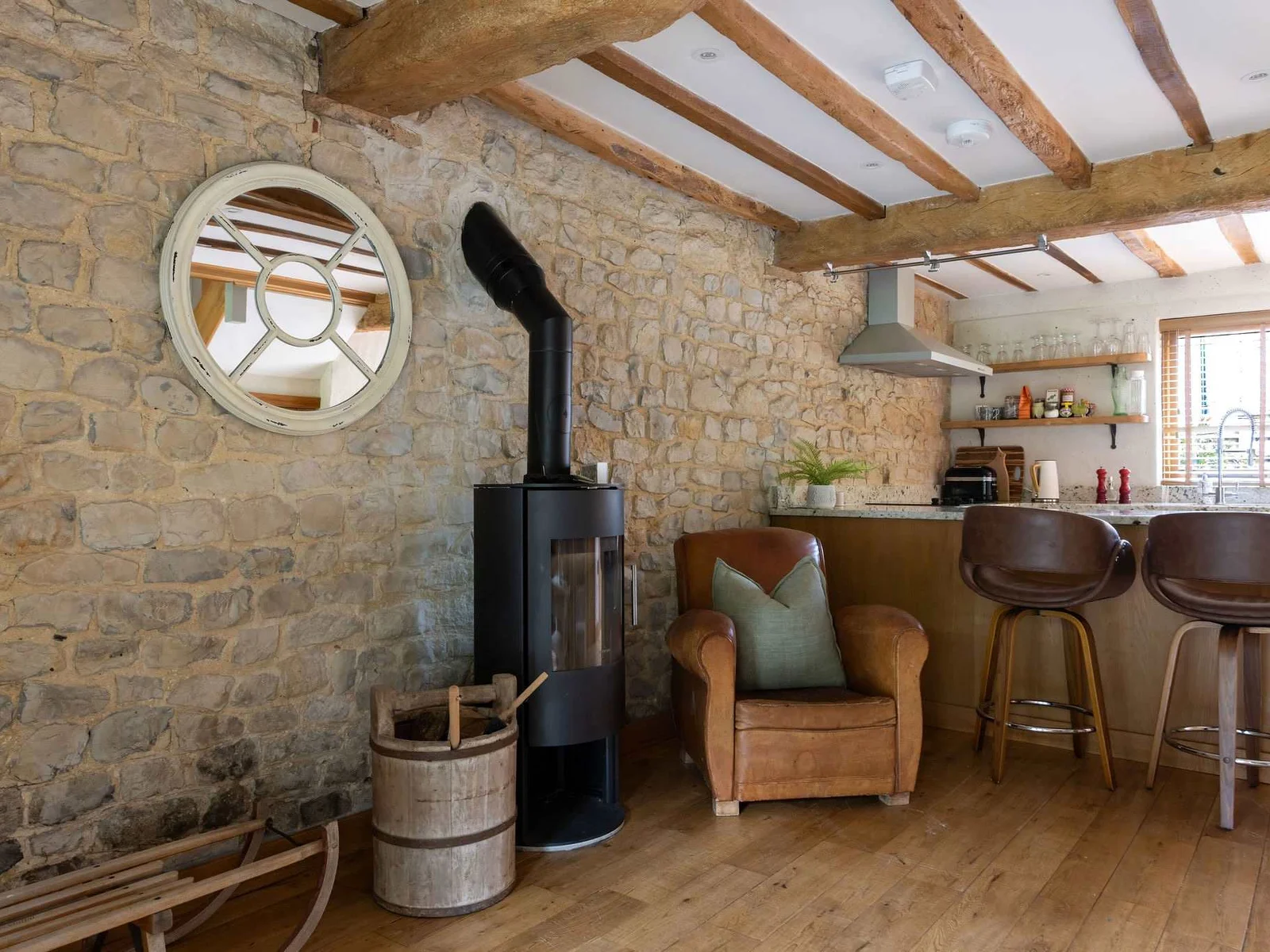 Characterful kitchen-living space with exposed stone, timber beams and a cosy wood-burning stove.