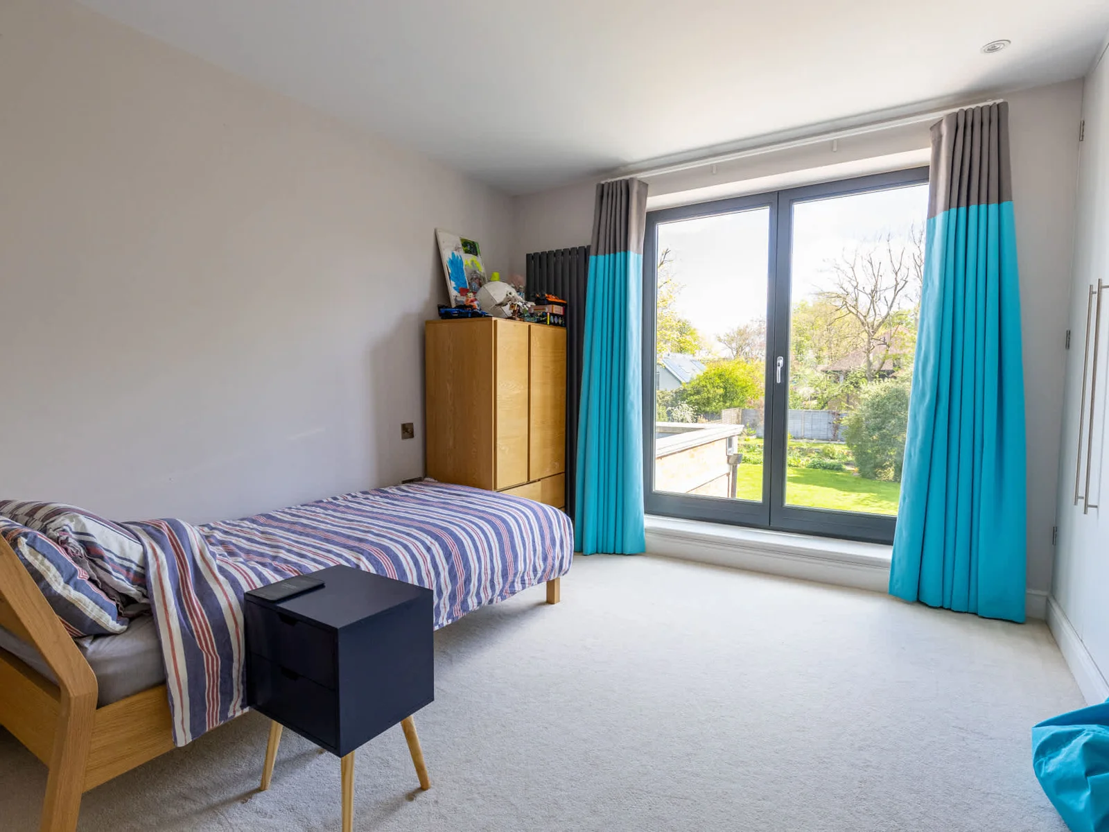 Bright bedroom with garden views and large window, offering a calm and comfortable space.