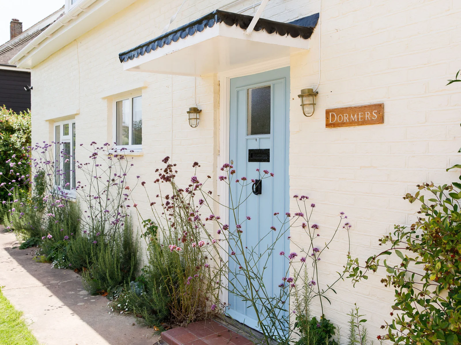 Pretty blue front door with flowering plants.