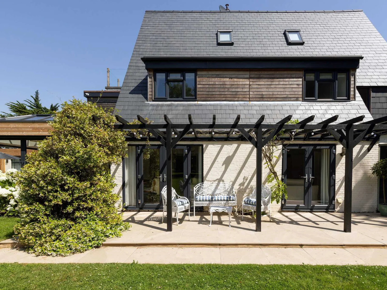 Contemporary holiday home exterior with covered terrace and inviting garden seating area
