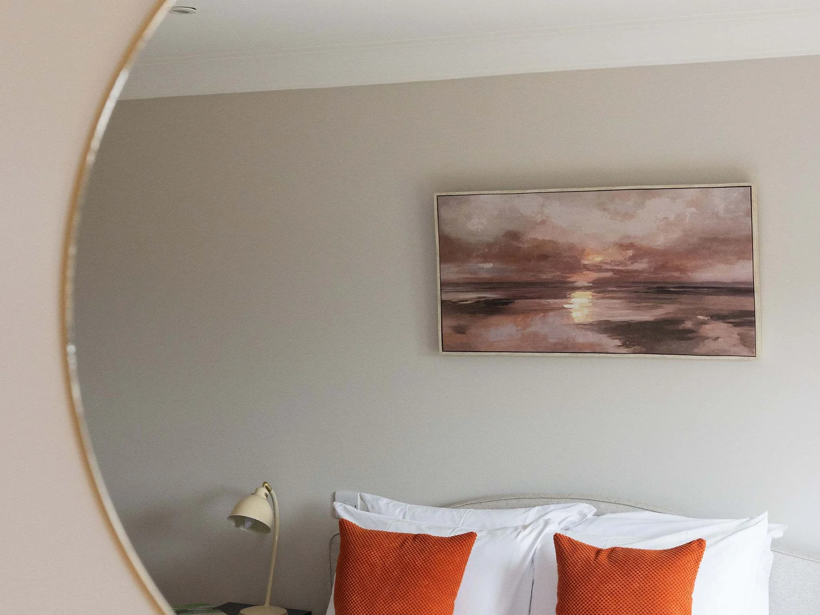 Thoughtful details throughout the master bedroom add a touch of character, with the round mirror beautifully framing the room beyond.