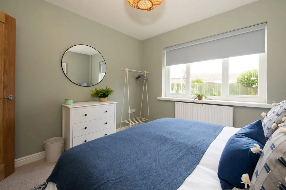 The room includes a clothing rail and chest of drawers