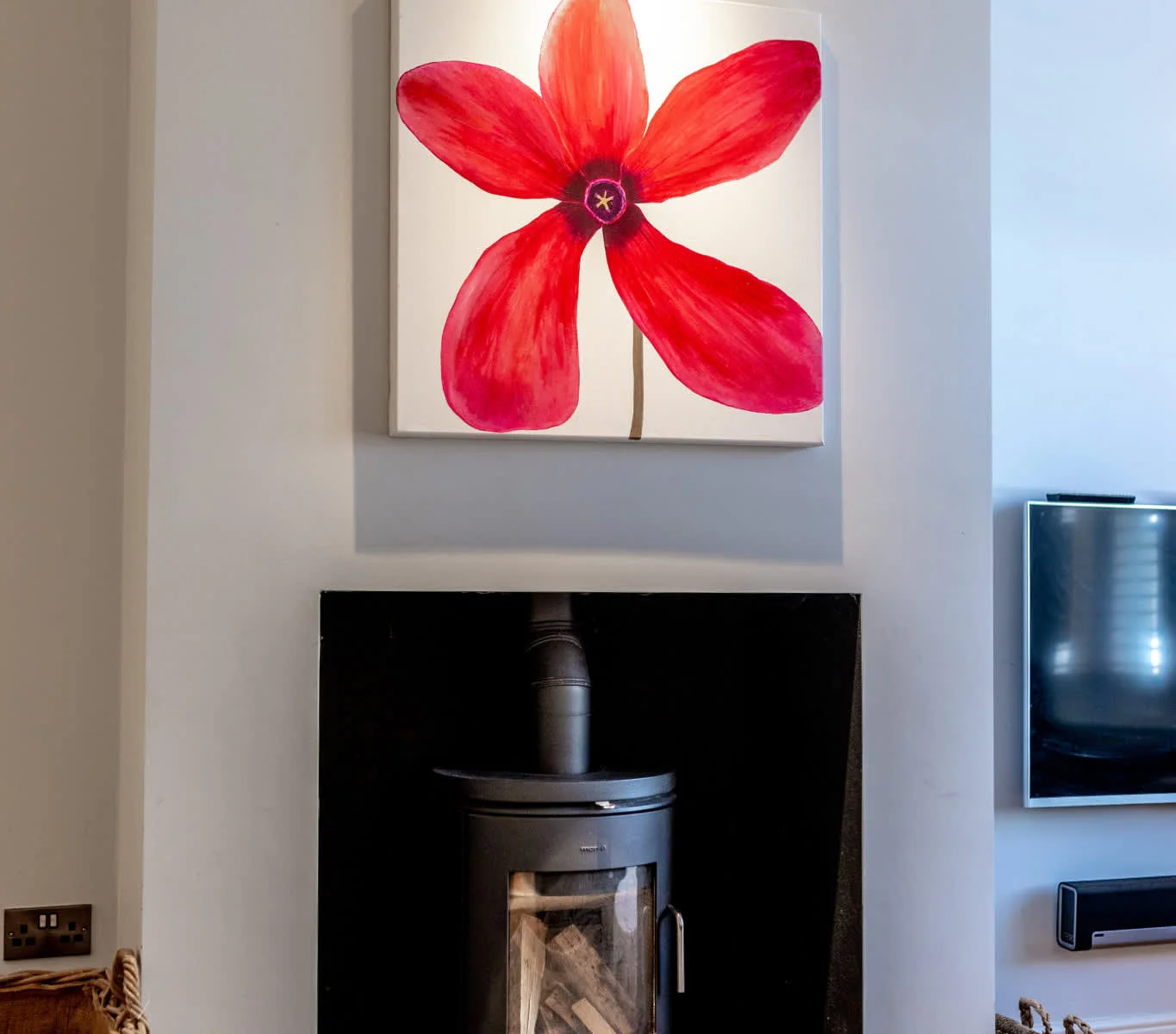 Stylish log burner with modern fireplace and statement artwork, creating a cosy focal point in the lounge.