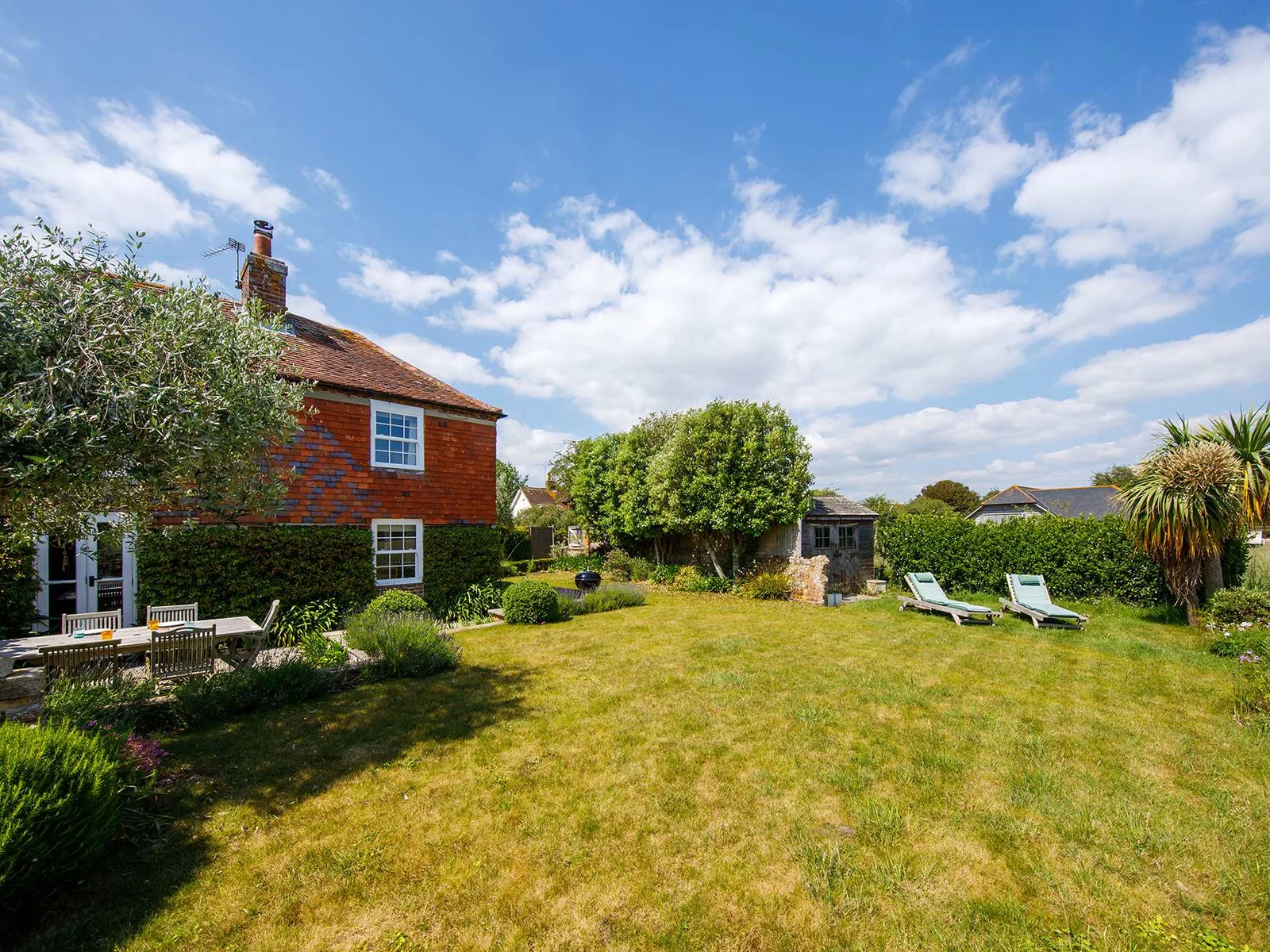 The expansive garden leads onto open farmland and the sea beyond