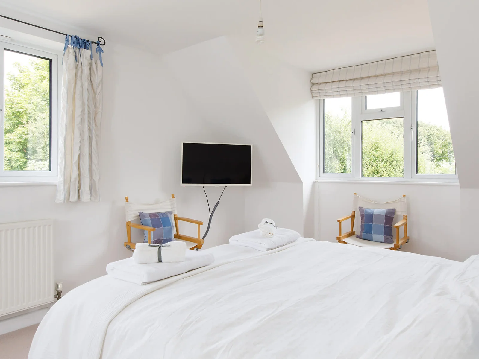 The master bedroom has a king bed, TV and two large windows looking out over the surrounding countryside.