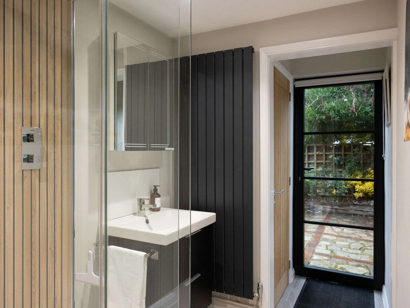 The downstairs shower room features a spacious walk-in shower with sleek fixtures and warm wood-effect detailing.