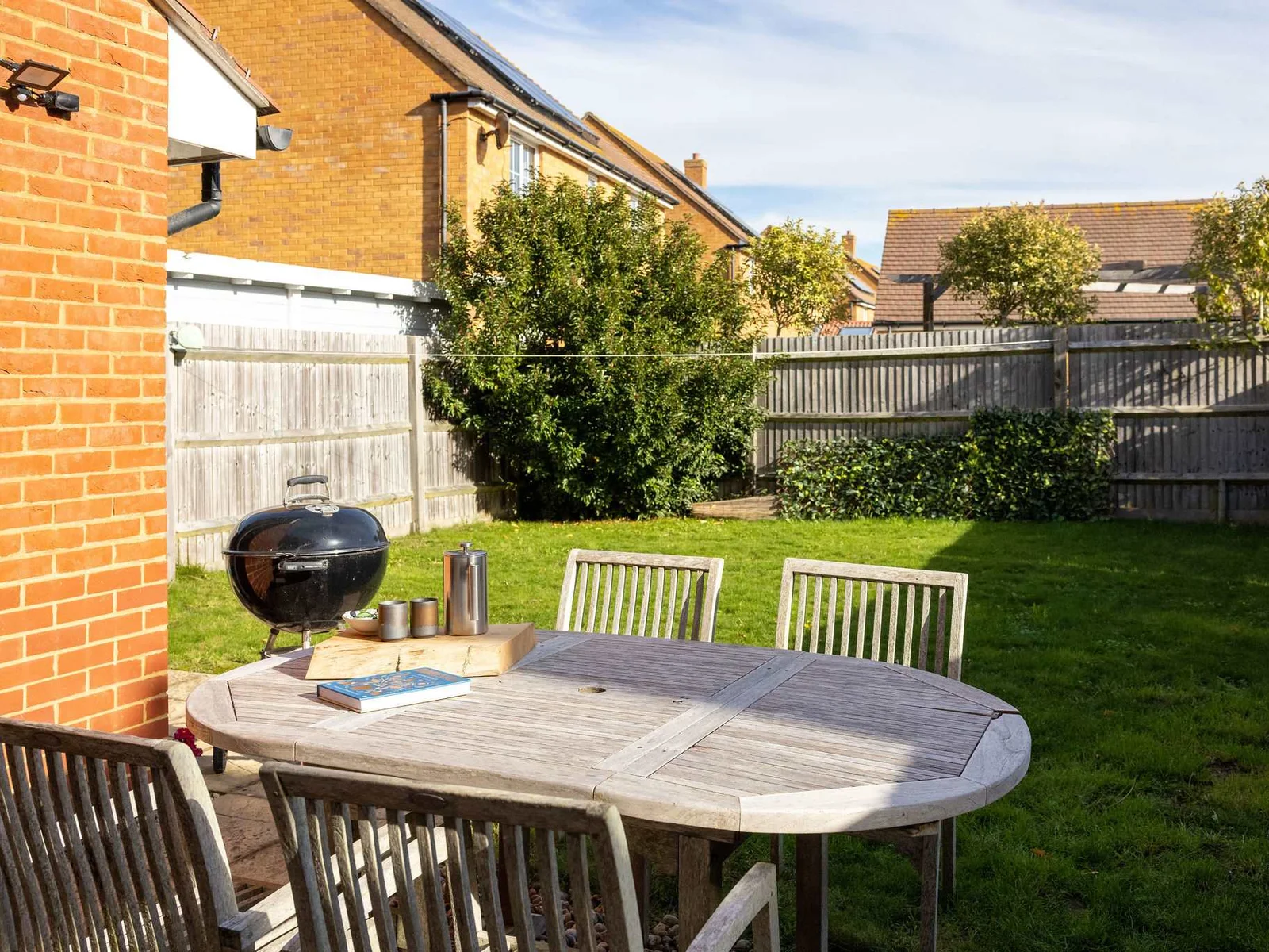 The sunny, enclosed garden with dining furniture and BBQ.
