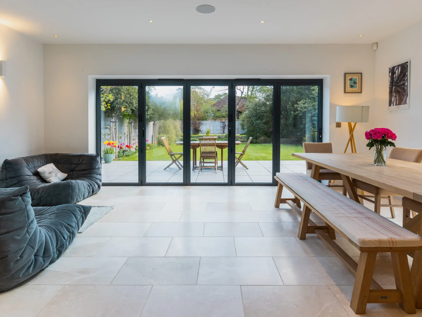 Open-plan dining and lounge with garden views and large bi-fold doors for seamless indoor-outdoor living.