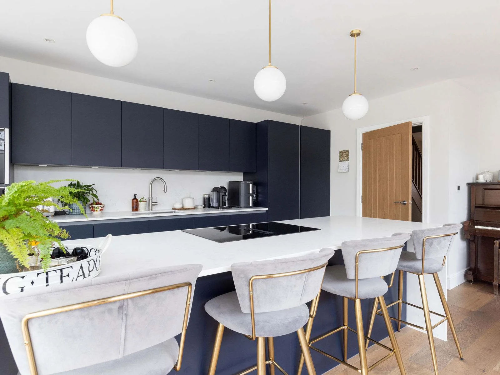The fully-equipped kitchen and dining area boasts a minimalist design with modern appliances and large breakfast bar with wooden stool seating.