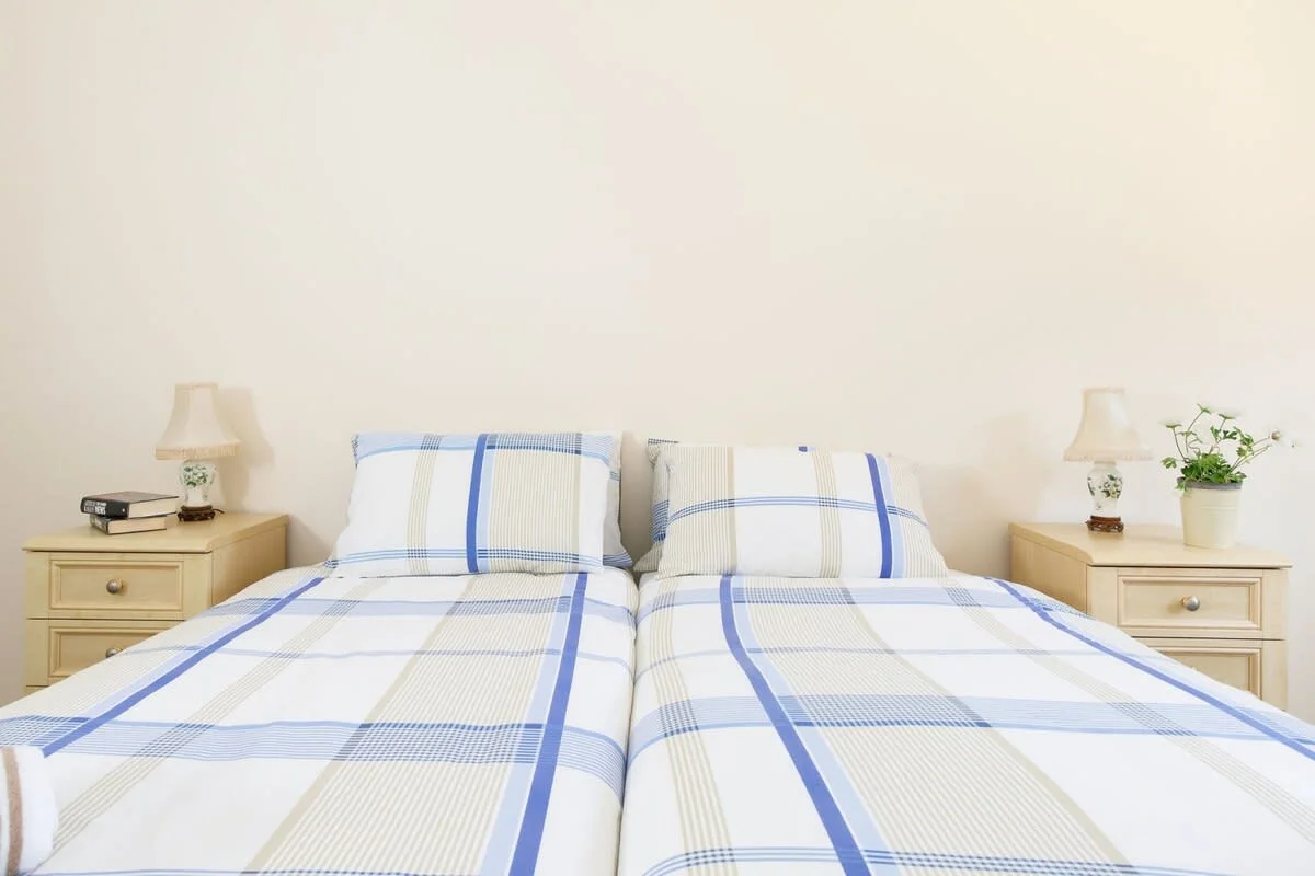 Bedside tables and reading lamps are found in both bedrooms.