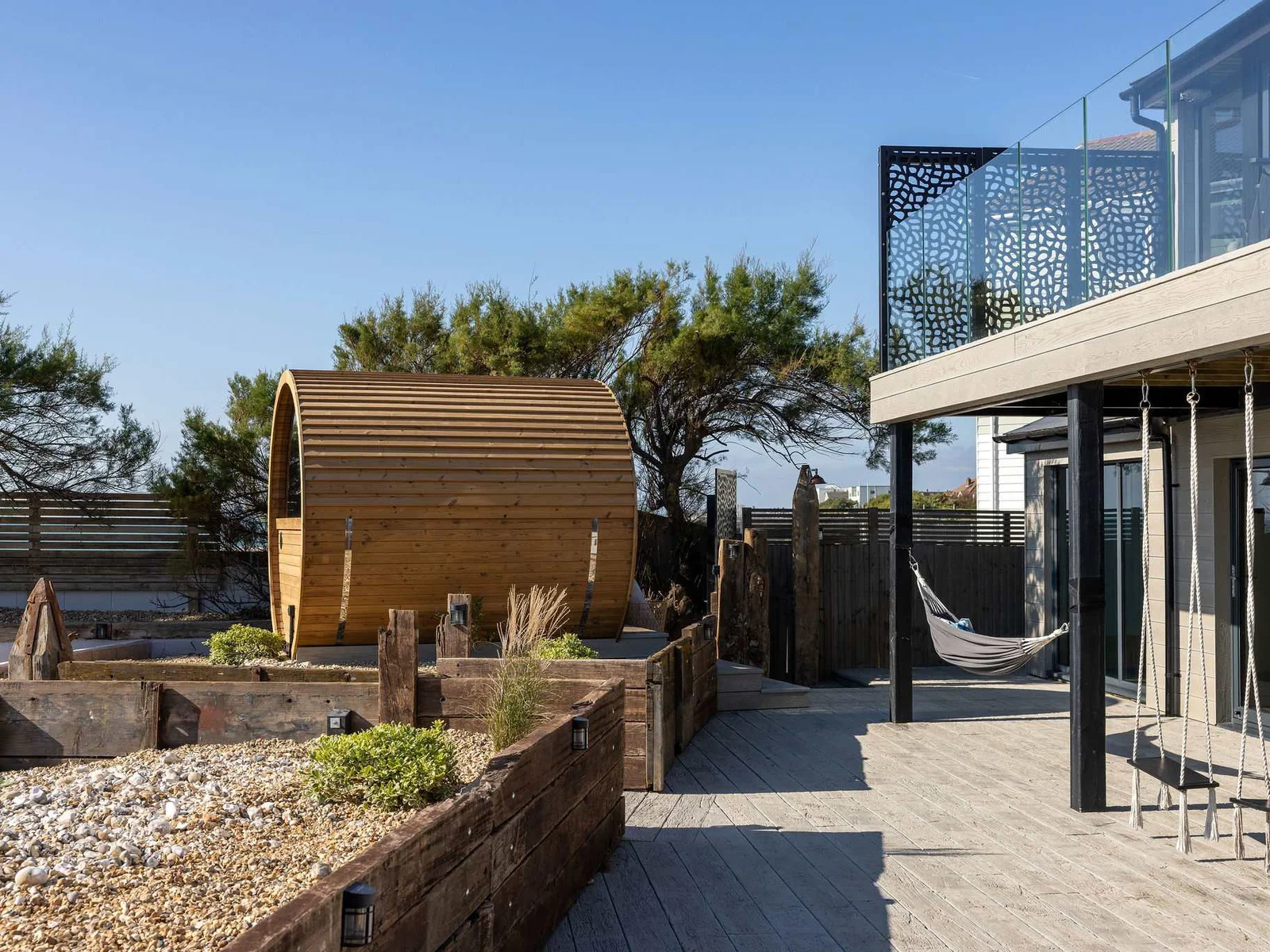 Newly laid decking surrounds the rear of the home, offering seating areas and direct beach access.