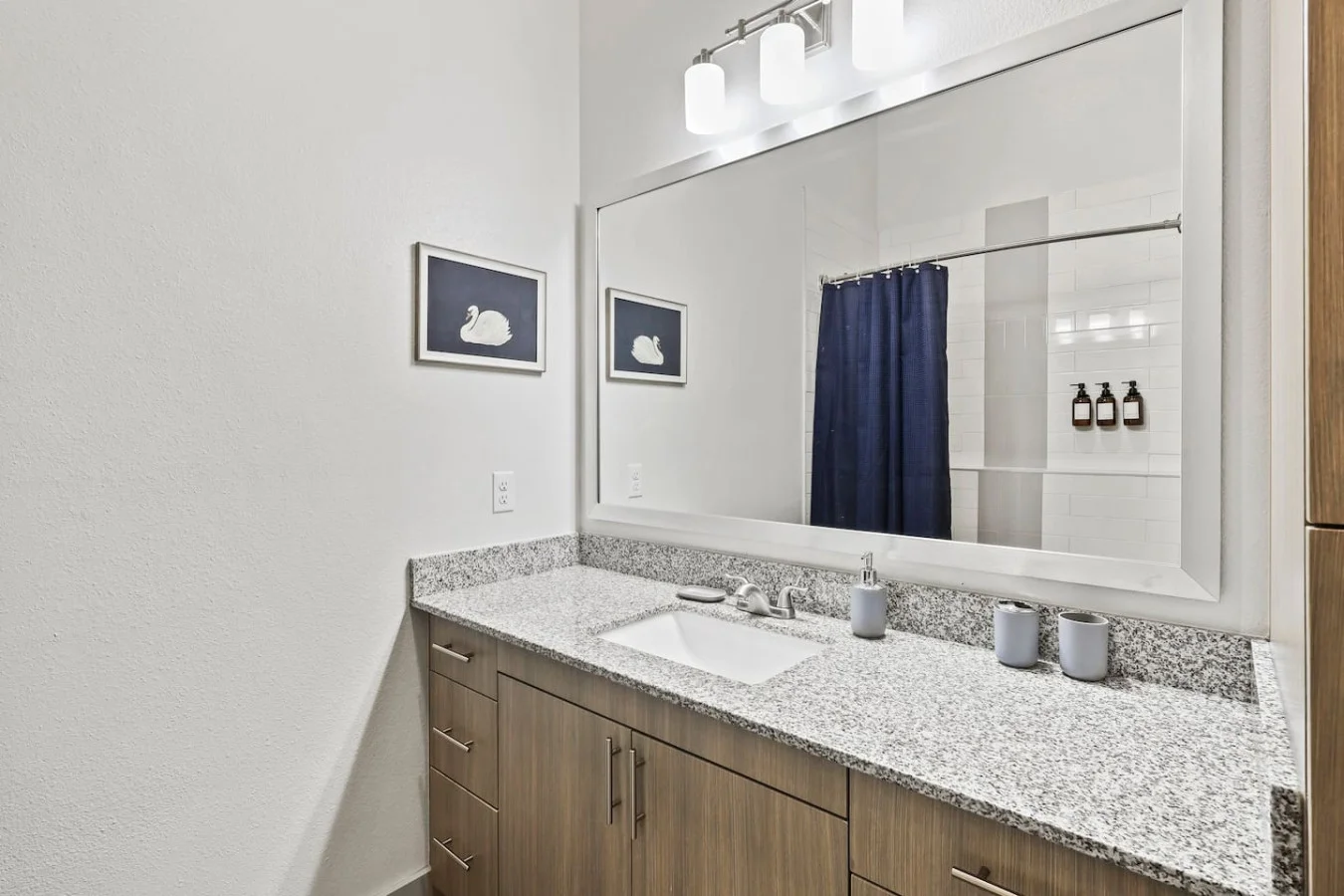 This bright and welcoming bathroom invites you to freshen up in comfort. Enjoy the forest-inspired shower curtain that adds a calming touch to your routine, complemented by the cozy rug underfoot and sparkling clean fixtures.