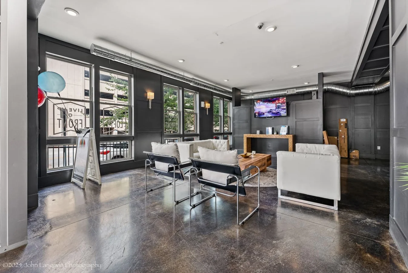Enjoy a stylish and welcoming living space featuring modern decor and a large flat-screen TV. The unique mirror reflects the vibrant "Good Vibes Only" sign, adding a playful touch to the ambiance. Perfect for relaxation and entertainment.
