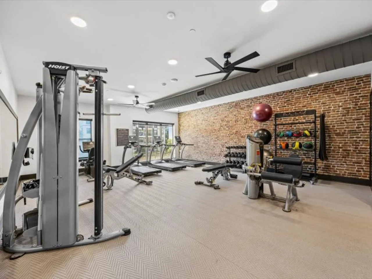 Spacious, well-lit gym equipped with a variety of cardio machines, free weights, and strength-training equipment.